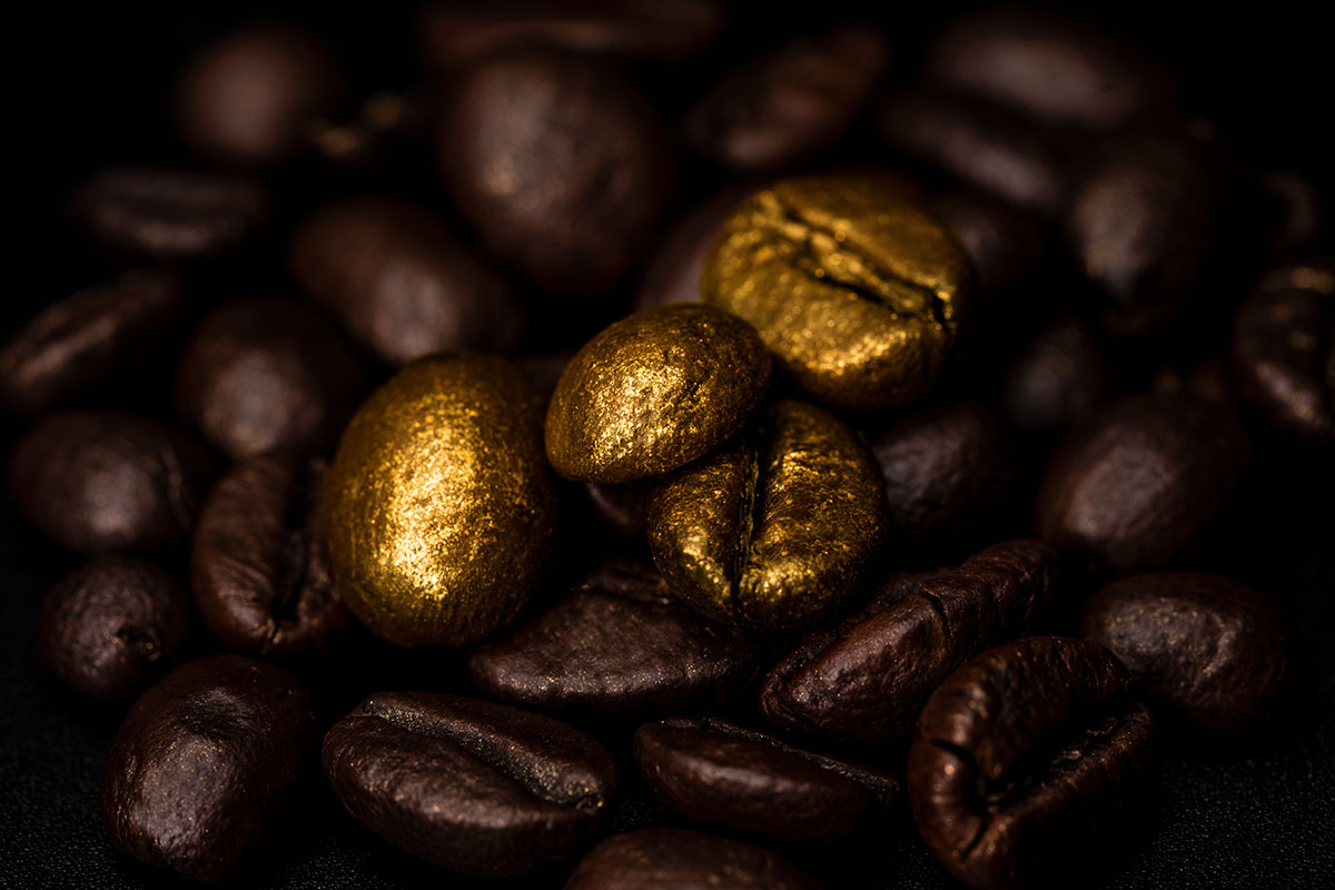 Zrna kave presvučena zlatom 24K među tamnim zrnima – Caffè 24K